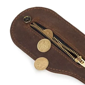 Brown Leather Medication or Coin Purse Belt Wallet. Close-up of a brown leather coin pouch with a zippered pocket partially open, revealing gold coins spilling out.